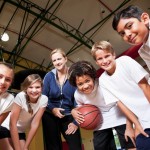 Group of children with coach playing basketball
